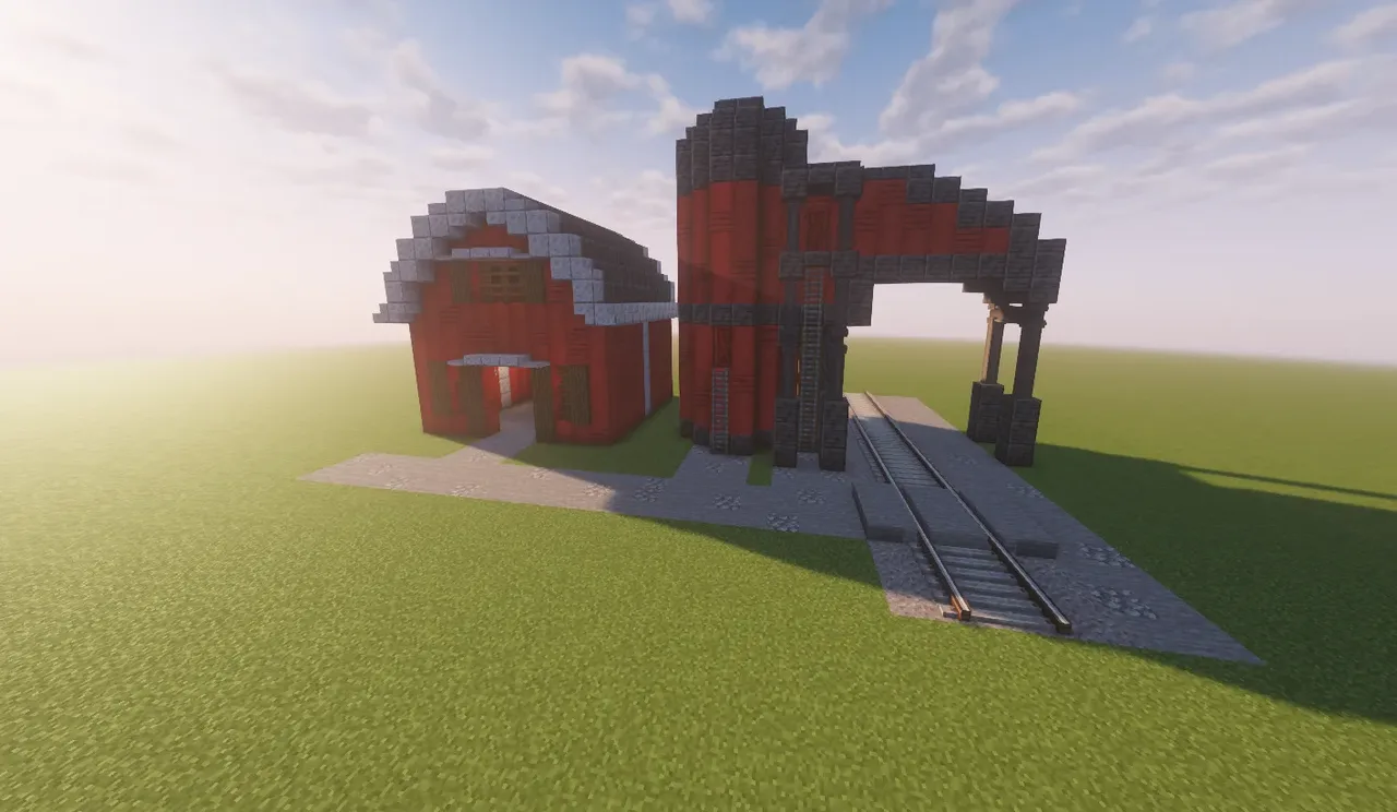 A simple barn with a silo and tracks.